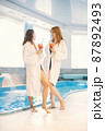 Two girls in a dressing gowns relaxing in a spa and holding a cocktails 87892493