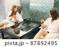 Two girls in a dressing gowns relaxing in a spa and holding a cocktails 87892495