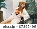 Young girl in a dressing gown relaxing in a spa and holding a cocktail 87892496