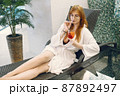 Young girl in a dressing gown relaxing in a spa and holding a cocktail 87892497