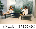 Two girls in a dressing gowns relaxing in a spa and holding a cocktails 87892498