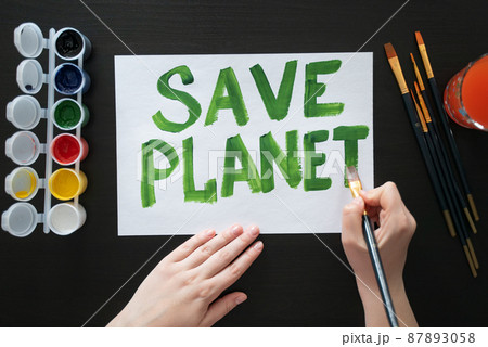 Human hands draw poster with paints and brush on blank sheet with call to save the planet. Rally, appeal, picket Human hands draw poster with paints and brush on blank sheet with call to save the planet. Rally, appeal, picket 87893058