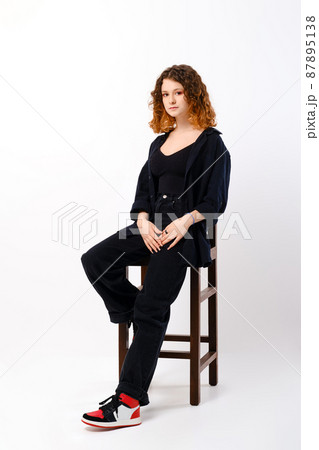 Young girl sitting on tall chair in studio Young girl sitting on tall chair in studio 87895138
