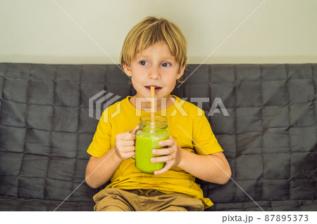 The boy is drinking Green tea latte with ice in mason jar. Homemade Iced Matcha Latte Tea with Milk zero waste 87895373