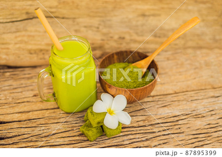 Green tea latte with ice in mason jar, matcha powder and candy made of matcha on wooden background. Homemade Iced Matcha Latte Tea with Milk zero waste Green tea latte with ice in mason jar, matcha powder and candy made of matcha on wooden background. Homemade Iced Matcha Latte Tea with Milk zero waste 87895399