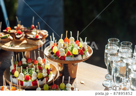 A table of various snacks, sandwiches, strawberries and other types of snacks. 87895852
