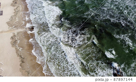 Aerial drone view flight over sea waves that roll onto sandy shore. Aerial drone view flight over sea waves that roll onto sandy shore. 87897144