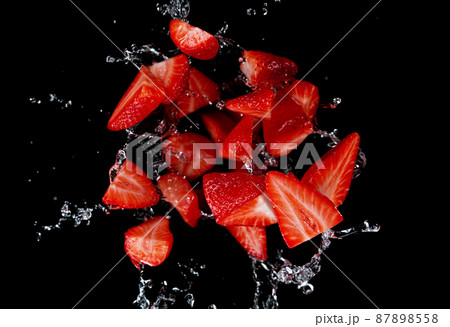 Freeze motion of sliced strawberries in water splash. 87898558
