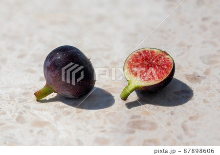 two ripe figs placed side by side, one is cut open two ripe figs placed side by side, one is cut open 87898606