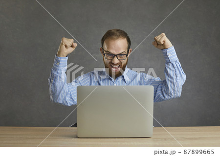 Yes, I did it. Happy euphoric ecstatic businessman in shirt and glasses sitting at table with laptop computer, celebrating success, fist pumping and shouting Hurray. Successful online business concept 87899665
