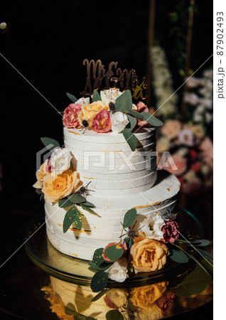 Beautiful wedding arch with flowers and a large wedding cake. 87902493