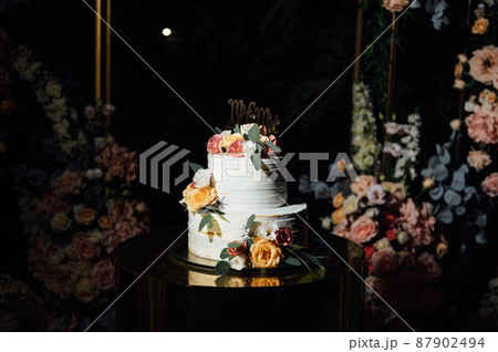 Beautiful wedding arch with flowers and a large wedding cake. Beautiful wedding arch with flowers and a large wedding cake. 87902494