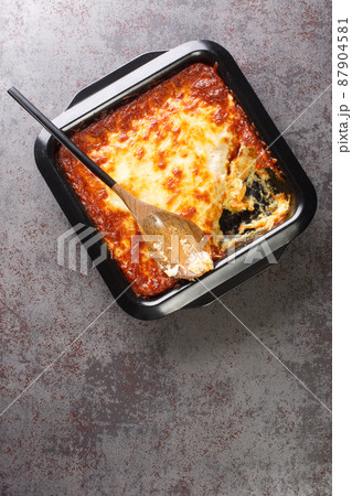 Bacalhau espiritual is a Portuguese casserole prepared with salt cod, carrot, bread, Bechamel sauce and topped with cheese closeup in the baking dish. Vertical top view Bacalhau espiritual is a Portuguese casserole prepared with salt cod, carrot, bread, Bechamel sauce and topped with cheese closeup in the baking dish. Vertical top view 87904581