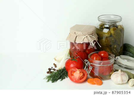 Jars of pickled vegetables and ingredients on white table Jars of pickled vegetables and ingredients on white table 87905354