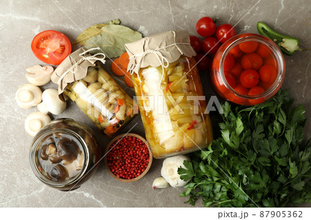 Jars of pickled vegetables and ingredients on gray textured table 87905362