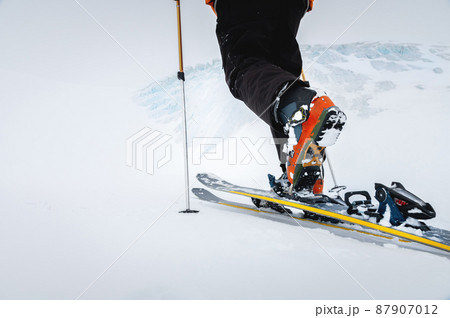 Close-up of freeride ski boots on snow. Skitour concept. Used worn boots on a male skier against the background of a glacier in cloudy weather in the mountains 87907012