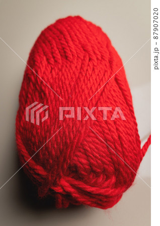 Red wool yarn Close-up of an unknitted piece of wool next to a ball of yarn. 87907020