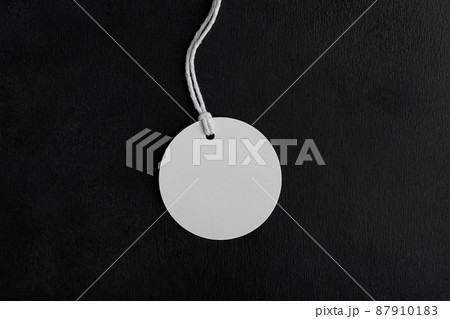Round white tag mockup with white cord, close up. Blank paper price tag isolated on black background Round white tag mockup with white cord, close up. Blank paper price tag isolated on black background 87910183