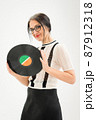 Studio photo of middle aged woman starting getting grey-haired wearing black and white clothes with vinyl record in hands on white background, middle age sexy lady, happy life concept 87912318