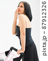 Studio photo of middle aged woman starting getting grey-haired wearing black clothes with silver disco ball in shopping basket white background, middle age sexy lady, happy life concept 87912326
