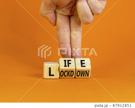 Life with lockdown symbol. Doctor turns wooden cubes and changes words 'lockdown' to'life'. Beautiful orange background. Covid-19 pandemic and life with lockdown concept. Copy space. 87912851