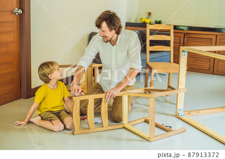 Father and son assembling furniture. Boy helping his dad at home. Happy Family concept 87913372