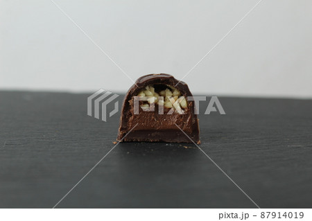 incision chocolate case candy stuffed with chocolate pralines and crushed peanuts close-up on a gray background with space for copyspace text. Chocolate Day Sweet Homemade Desserts 87914019