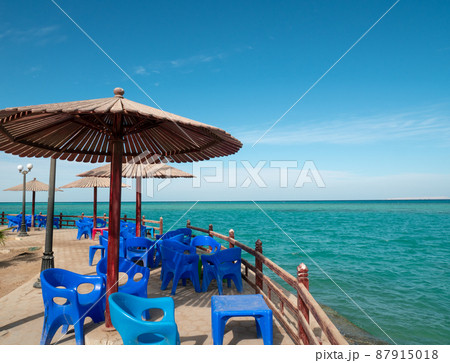 Beach cafe with plastic furniture, wood parasols 87915018