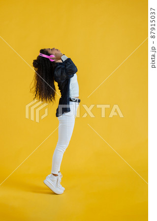 young african american woman listening to music with headphones doing a tiptoe young african american woman listening to music with headphones doing a tiptoe 87915037
