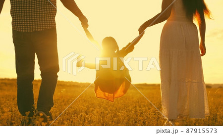 happy family park. little kid daughter runs across meadow sunset. mother father kid child travel together. childhood dream run and play. family walk sunshine. cheerful child holds mom dad by hand 87915573