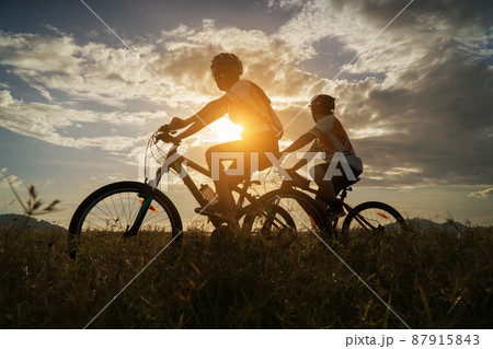 Young Couple in love fun and happy riding mountain bike after covid-19 coronavirus outbreak. End of the coronavirus outbreak. Silhouette cycling man and woman riding mountain bike at sunset time. 87915843