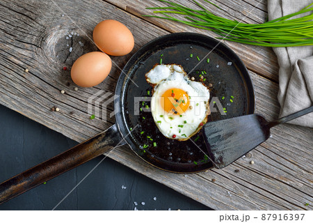 Crunchy fried egg served in an iron frying pan on rustic weathered wood 87916397