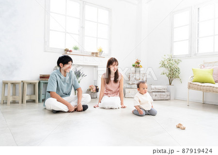 部屋で遊ぶ赤ちゃんとそれを見守る両親 部屋で遊ぶ赤ちゃんとそれを見守る両親 87919424
