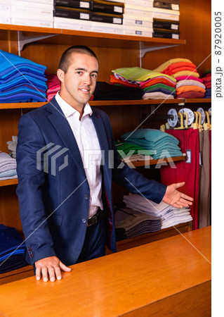 Competent smiling salesman offering new trendy textiles of high quality for dressmaking in textile shop Competent smiling salesman offering new trendy textiles of high quality for dressmaking in textile shop 87920005