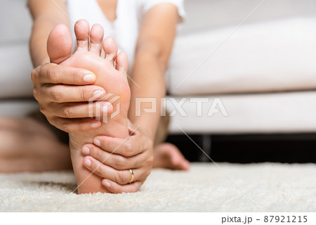 Asian woman feeling pain in her foot at home Asian woman feeling pain in her foot at home 87921215