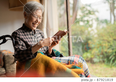 老人ホームで車椅子に乗り読書するシニア女性 87921819