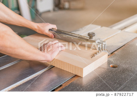 Unrecognizable carpenter sawing wooden plank in workshop 87922717