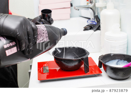 hairdresser holding bowl and preparing hair dye in beauty salon close. 87923879