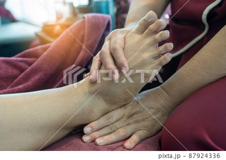 Woman receiving foot massage service from masseuse Woman receiving foot massage service from masseuse 87924336