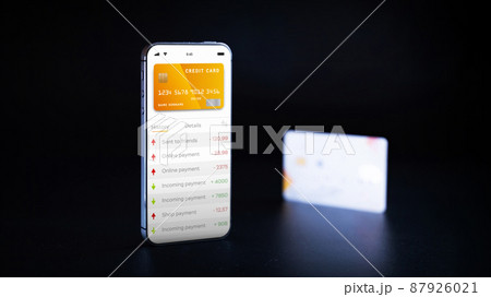 Mobile banking application. Mobile phone with internet online bank app. Credit card on black background. Save money business wallet. 87926021
