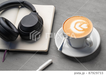 Coffee cup with a note book and headphones on gray background Coffee cup with a note book and headphones on gray background 87929733