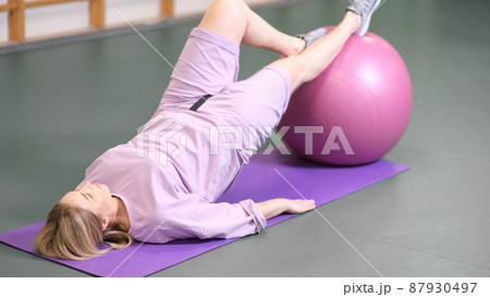 woman doing bridge using fitball in a fitness club. pilates workout exercise. real people woman doing bridge using fitball in a fitness club. pilates workout exercise. real people 87930497