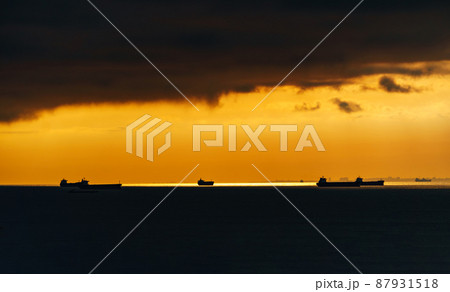 silhouettes of ships at sea against a bright sunset sky, sunlight reflected from the waves, dramatic sky silhouettes of ships at sea against a bright sunset sky, sunlight reflected from the waves, dramatic sky 87931518