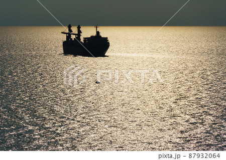 silhouettes of ship at sea, dramatic seascape with sunset sky, bright sunlight reflected from the waves silhouettes of ship at sea, dramatic seascape with sunset sky, bright sunlight reflected from the waves 87932064