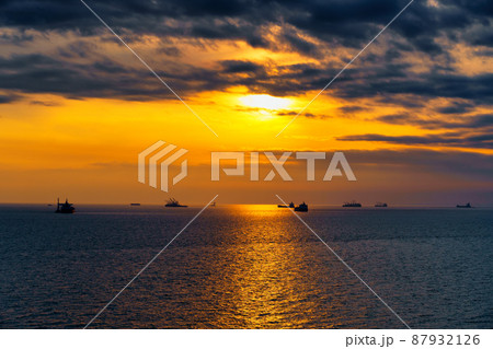 Beautiful sunset in the sea and ships. The sun shines through the clouds and is reflected in the waves 87932126