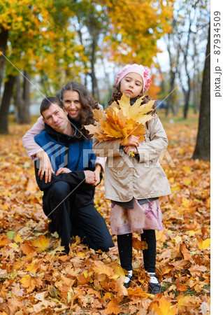 Portrait of a family in an autumn park. Happy parents and unhappy child posing with yellow leaves. Portrait of a family in an autumn park. Happy parents and unhappy child posing with yellow leaves. 87934509