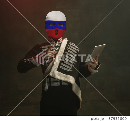 Portrait in mixed style. Young men, medieval hussar wearing red, blue and white colors balaclava on dark background. Concept of comparison of eras. Stop war conflict, crisis Portrait in mixed style. Young men, medieval hussar wearing red, blue and white colors balaclava on dark background. Concept of comparison of eras. Stop war conflict, crisis 87935800