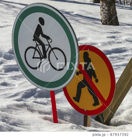 Road signs: permitting the passage of cyclist and prohibiting the movement of  pedestrian against the background of snow.  87937392