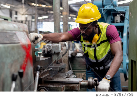 Engineering male african american wear hardhat working at machine in factory. 87937759