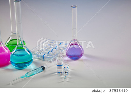 Four medical flasks with colorful chemical reagents. Seven mockup ampoules with transparent liquid and syringe isolated on white. Coronavirus Four medical flasks with colorful chemical reagents. Seven mockup ampoules with transparent liquid and syringe isolated on white. Coronavirus 87938410